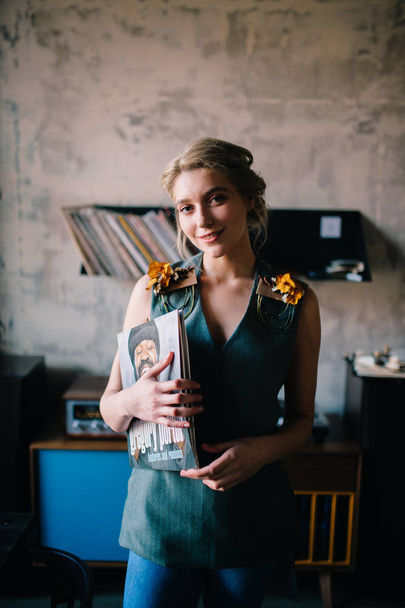 young beautiful woman in old fashioned clothing with vinyl record in retro cafe with gramophone - Foto, Bild