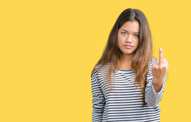 Молодая красивая брюнетка в полосатых свитерах на изолированном фоне демонстрирует средний палец, невежливое и грубое выражение лица
 - Фото, изображение