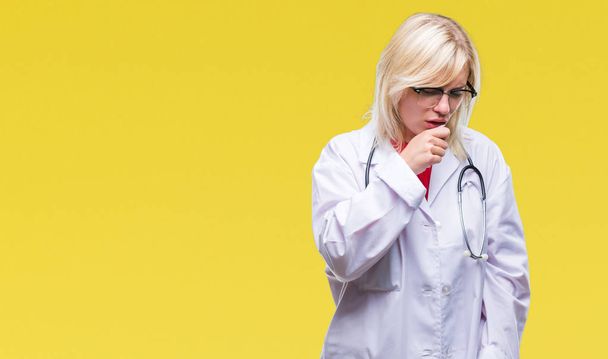 Młoda piękna Blondynka lekarz kobieta ubrana uniform medyczny na białym tle, ogólne złe samopoczucie i kaszel jako objaw na zimno lub zapalenie oskrzeli. Pojęcie opieki zdrowotnej. - Zdjęcie, obraz