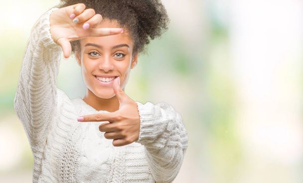 Nuori afro amerikkalainen nainen yllään talvi villapaita yli eristetty tausta hymyilevä tehdä runko kädet ja sormet onnellinen kasvot. Luovuus ja valokuvaus käsite
. - Valokuva, kuva
