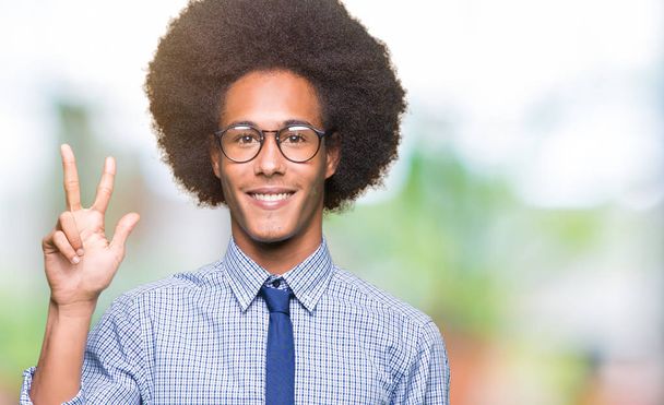 Young african american business man with afro hair wearing glasses showing and pointing up with fingers number three while smiling confident and happy. - Photo, Image