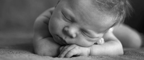Egy újszülött csecsemő alszik a gyomrára, tegye a kezét a feje alá. Tónusú - Fotó, kép