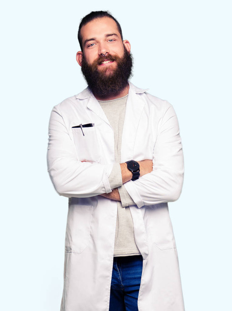 Young blond scientist man wearing white coat happy face smiling with crossed arms looking at the camera. Positive person. - Foto, Bild