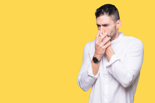 Young business man over isolated background smelling something stinky and disgusting, intolerable smell, holding breath with fingers on nose. Bad smells concept. - Photo, Image