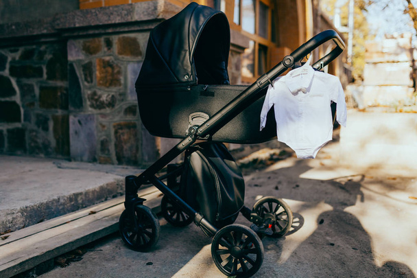 cochecito de bebé moderno negro en la luz solar
  - Foto, imagen