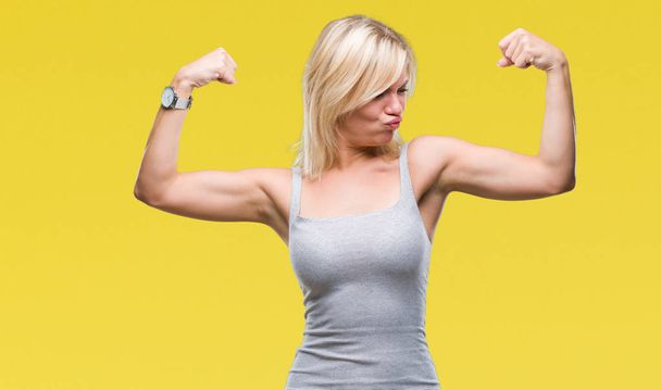 Young beautiful blonde woman over isolated background showing arms muscles smiling proud. Fitness concept. - Fotoğraf, Görsel