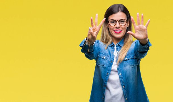 Young beautiful woman over wearing glasses over isolated background showing and pointing up with fingers number eight while smiling confident and happy. - Photo, Image