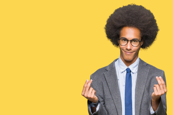 Jeune homme d'affaires afro-américain avec des cheveux afro portant des lunettes Faire un geste d'argent avec la main, demander le paiement du salaire, millionnaire entreprise
 - Photo, image