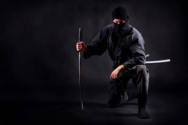 Ninja samurai crouched on one leg  and propped on a sword - Foto, imagen