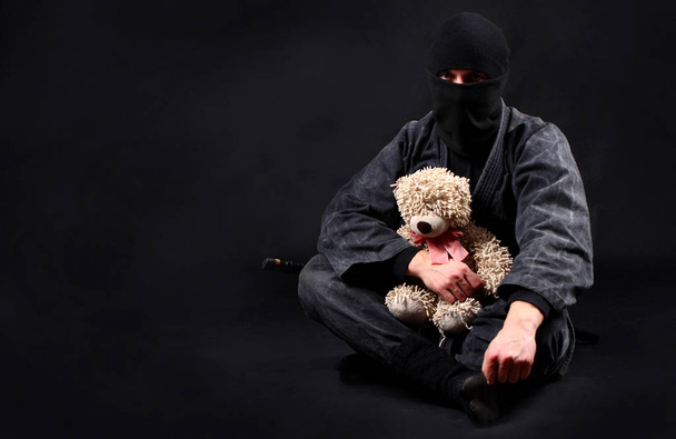 Ninja with teddy bear. Good and strength. Protection of the weak concept. - Fotografie, Obrázek