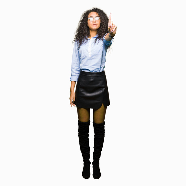 Mladé krásné obchodní dívka s kudrnatými vlasy nosit brýle ukázání prstem nahoru a rozzlobený výraz - Fotografie, Obrázek