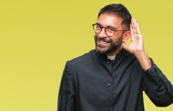 Дорослий іспаномовний католицький священик над ізольованим тлом посміхається рукою через вухо слухаючи чутки або плітки. Концепція глухоти
. - Фото, зображення
