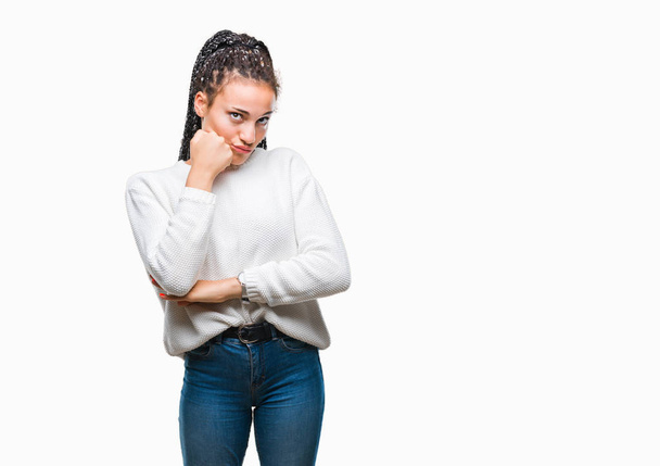 Young gevlochten hair Afrikaans Amerikaans meisje winter trui dragen over geïsoleerde achtergrond met hand op kin denken over de vraag, nadenkend expressie. Glimlachend met doordachte gezicht. Twijfel concept. - Foto, afbeelding