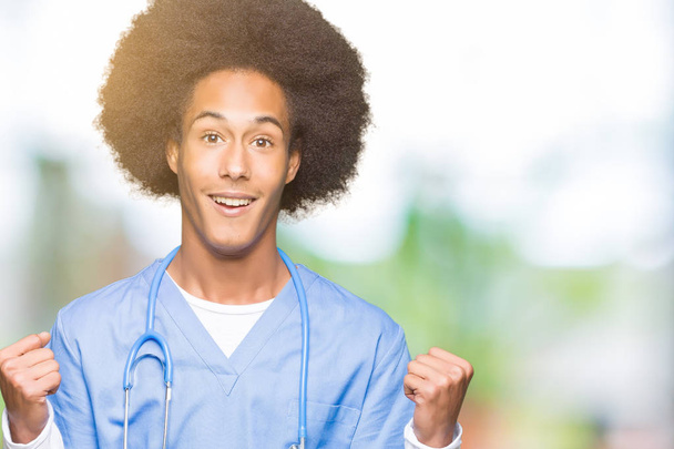 Fiatal afro-amerikai orvos ember afro haj ünnepli meglepett, és lenyűgözött a siker emelt karokkal, és nyitott szemmel. Győztes koncepció. - Fotó, kép