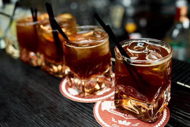 Four alcoholic cocktails whiskey with cola and lemon in glasses  - Foto, Imagem