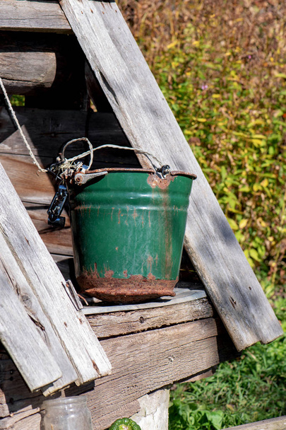ein alter Brunnen mit einem Eimer in einem europäischen Dorf. - Foto, Bild