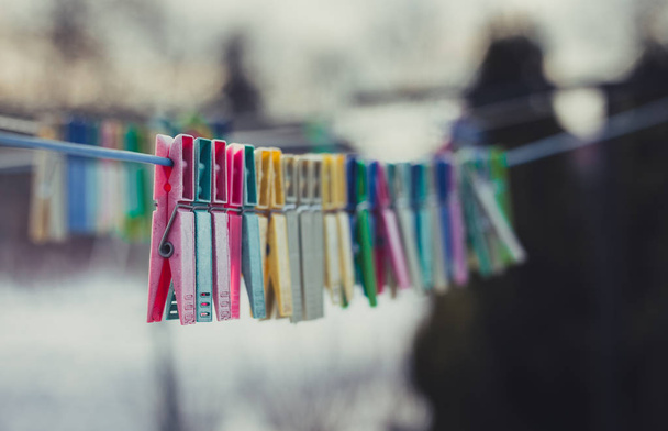 Hermosas pinzas de ropa de colores en la línea de lavado con nieve en el fondo en invierno
. - Foto, imagen