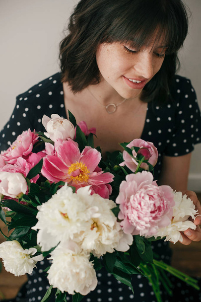 Krásná brunetka v vintage šatech drží moderní kytice s růžové a Bílé pivoňky. Happy elegantní žena s Pivoňka květiny v pokoji. Mezinárodní den Dámské - Fotografie, Obrázek