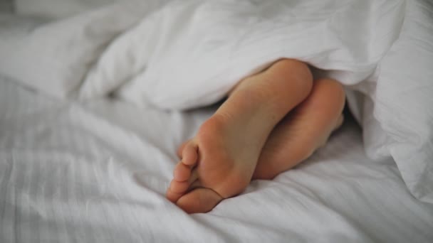 Male foots in bed under blanket - Footage, Video
