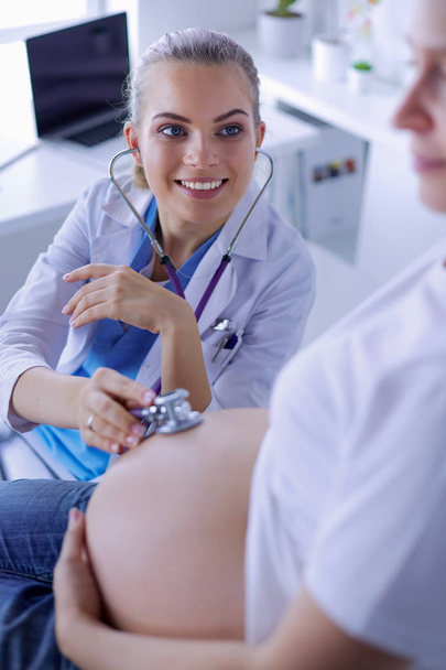 Mladá žena lékař vyšetřuje těhotnou ženu na klinice. - Fotografie, Obrázek