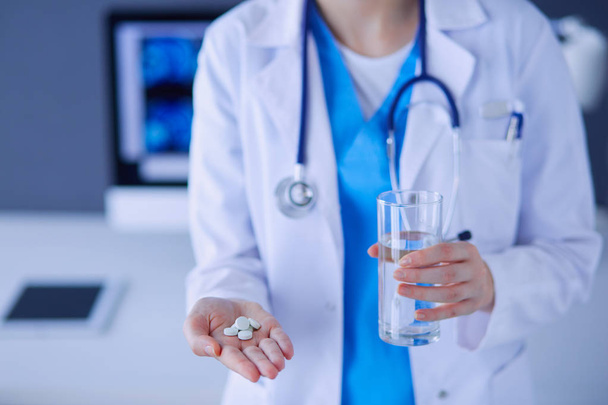 Close-up shot of doctors hands holding pills and glass of water. - Фото, зображення