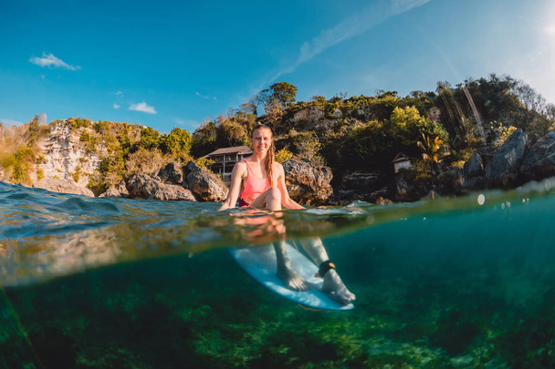 Chica surfista feliz con tabla de surf. Surfista sentado a bordo en el océano
. - Foto, Imagen