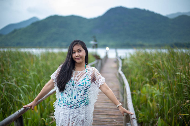 Young woman stands on a wooden bridge on the nature background - 写真・画像
