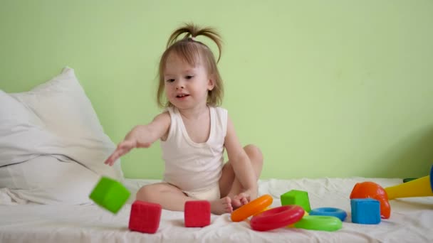 Klein kind is herstellen in de medische faciliteit, zittend op bed en spelen in kleurrijke zachte kubussen en piramide en glimlacht. Herstel voor kid in ziekenhuis ward - Video