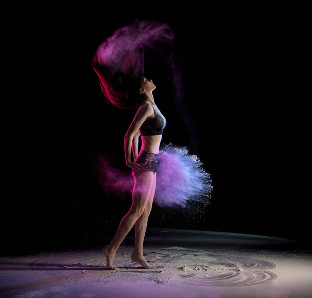 Young woman shaking hair and throwing chalk while dancing  - Foto, Imagen