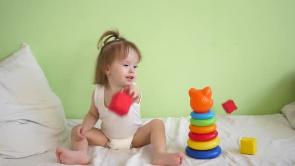 Kis gyermek visszaszerzés egészségügyi intézményben, ül ágyas és színes puha kockákra, a piramis és a mosoly játszik. Gyerek kórházi osztályon visszanyerése - Felvétel, videó