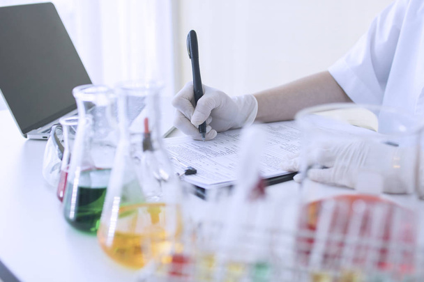 ученый экспериментирует с химической жидкостью и письменной информацией на бумаге в лаборатории
 - Фото, изображение