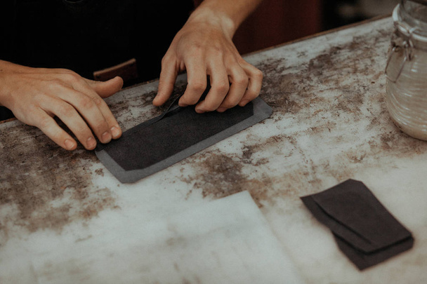 Close up of leather craftsman working with natural leather. Handmade master at work in local workshop. Handmade concept. - Foto, afbeelding