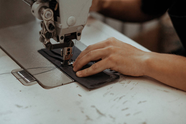 Close up of sewing machine working part with leather. The masters hands sews a leather product. Handmade concept. - Foto, imagen