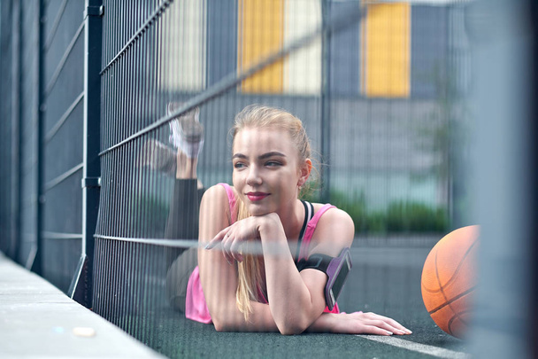 Beautiful young woman playing basketball outdoors. The girl on the sports ground - Fotó, kép