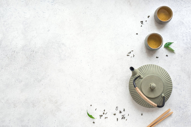 グリーン ティー セット - 鉄のティーポットと茶葉とセラミック茶碗。白い背景のコピー スペース平面図上の伝統的なアジアのお茶の組成. - 写真・画像
