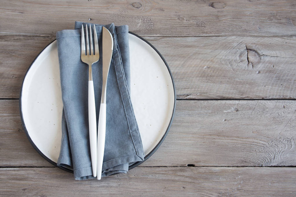 Natural table setting - plain ceramic plate, linen napkin, cutlery on wooden table. Eco-friendly concept, nordic style. - Foto, Imagem