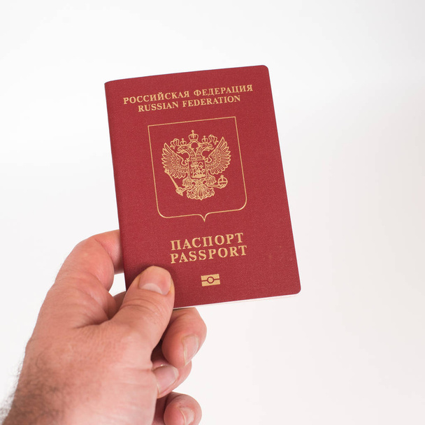 Mano del hombre sosteniendo pasaporte internacional ruso aislado sobre fondo blanco
. - Foto, Imagen