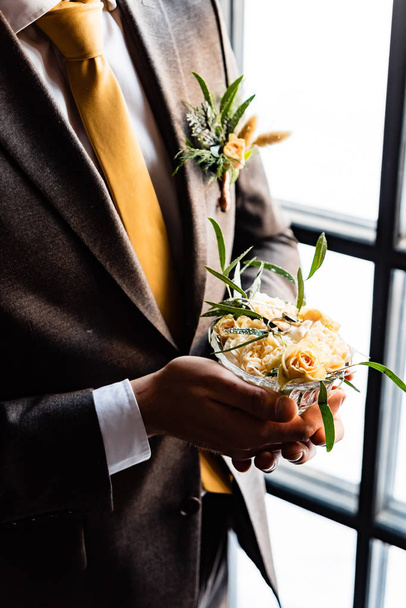 Stylish groom holding  white wedding bouquet. Young groom in a suit.  - Photo, Image