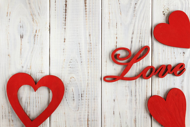 Wooden letters love and red hearts on a white wooden background. Background or postcard - Foto, afbeelding