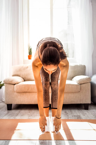 Concentrated sporty girl doing stretching exercises - 写真・画像