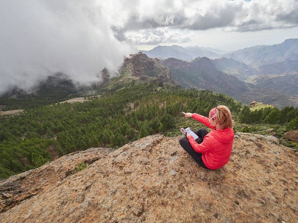 Τουριστικά νέα γυναίκα κάθεται στην άκρη του βράχου, διαβούλευση με χάρτη, Γκραν Κανάρια, Ισπανία - Φωτογραφία, εικόνα