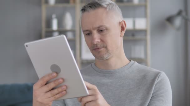 Mann mit grauen Haaren nutzt Tablet am Arbeitsplatz - Filmmaterial, Video