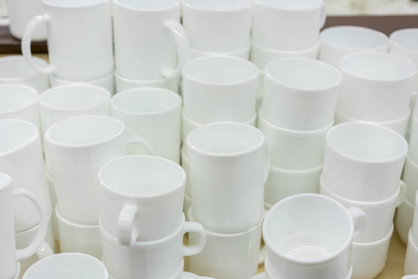 Mağaza rafındaki beyaz su bardağı. Beyaz seramik kahve bardak ve tabaklar raflarda. Raflar mutfak gereçleri ile - Fotoğraf, Görsel