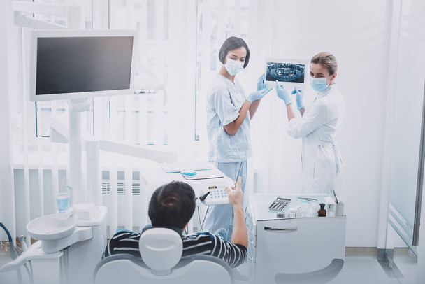 Cheerful young international dentist demonstrating roentgen picture - Photo, image