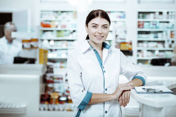 Chica encantada positiva que trabaja en la farmacia
 - Foto, imagen