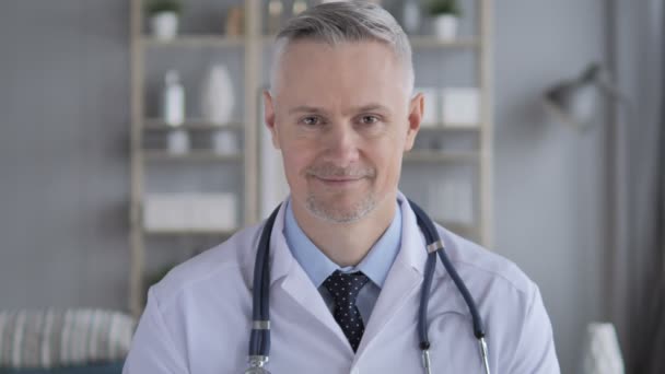 Portret uśmiechający się dodatnie lekarz z siwych włosów - Materiał filmowy, wideo