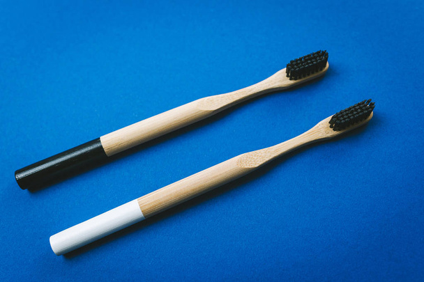 Duas escovas de dentes de bambu isoladas em fundo azul
 - Foto, Imagem