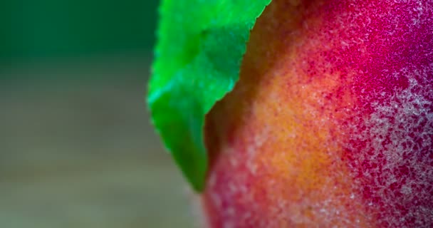 A large ripe juicy peach with a green leaf, slowly rotates in front of the camera - Кадри, відео