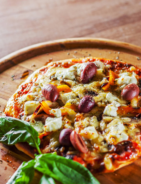 vejetaryen pizza Mozzarella peynir, zeytin, mantar, biber ve taze fesleğen. Ahşap masa arka plan üzerinde İtalyan pizza - Fotoğraf, Görsel