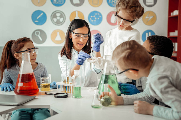 Competent young scientist teaching her delighted pupils - Foto, imagen